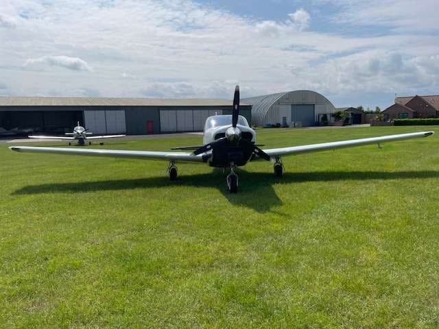 Front view of a light blue and white aircraft on a grassy field.