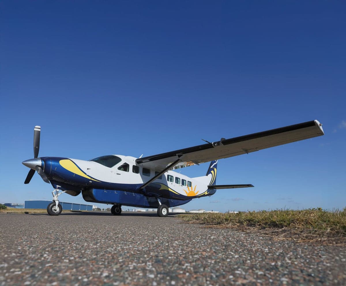 Side view of a blue and white turboprop aircraft on the tarmac.