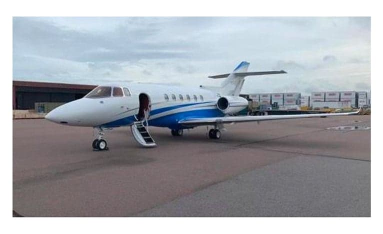 A Hawker jet with blue and white paint scheme is parked on the tarmac with the stairs down.