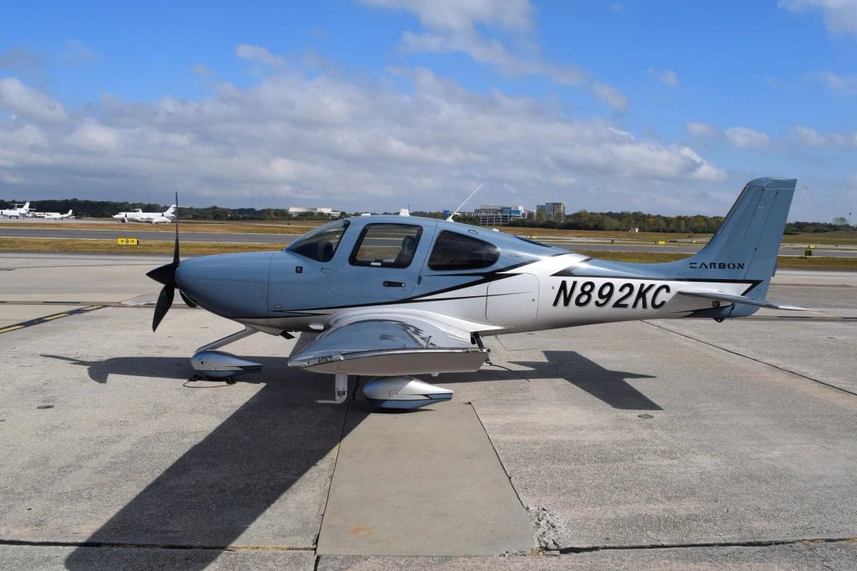 A Cirrus SR22T aircraft with a blue and silver paint scheme is parked on the tarmac.