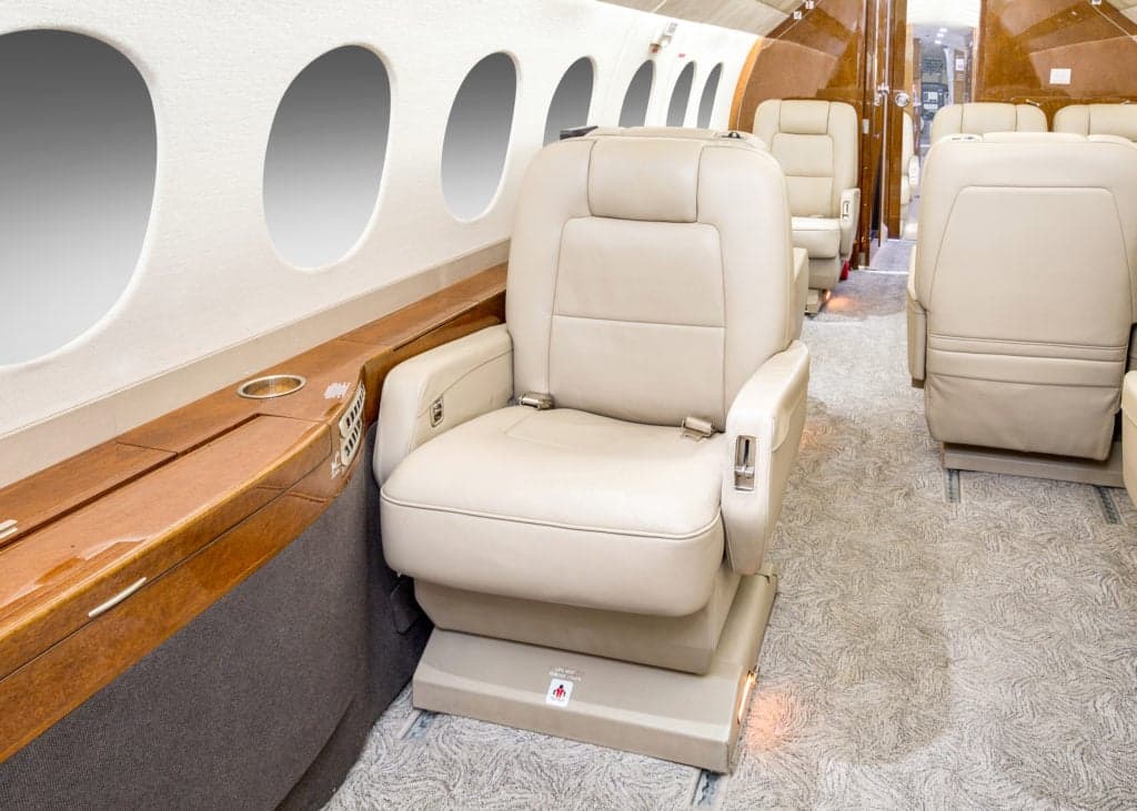 Interior view of the aircraft cabin with leather seats and wood trim.