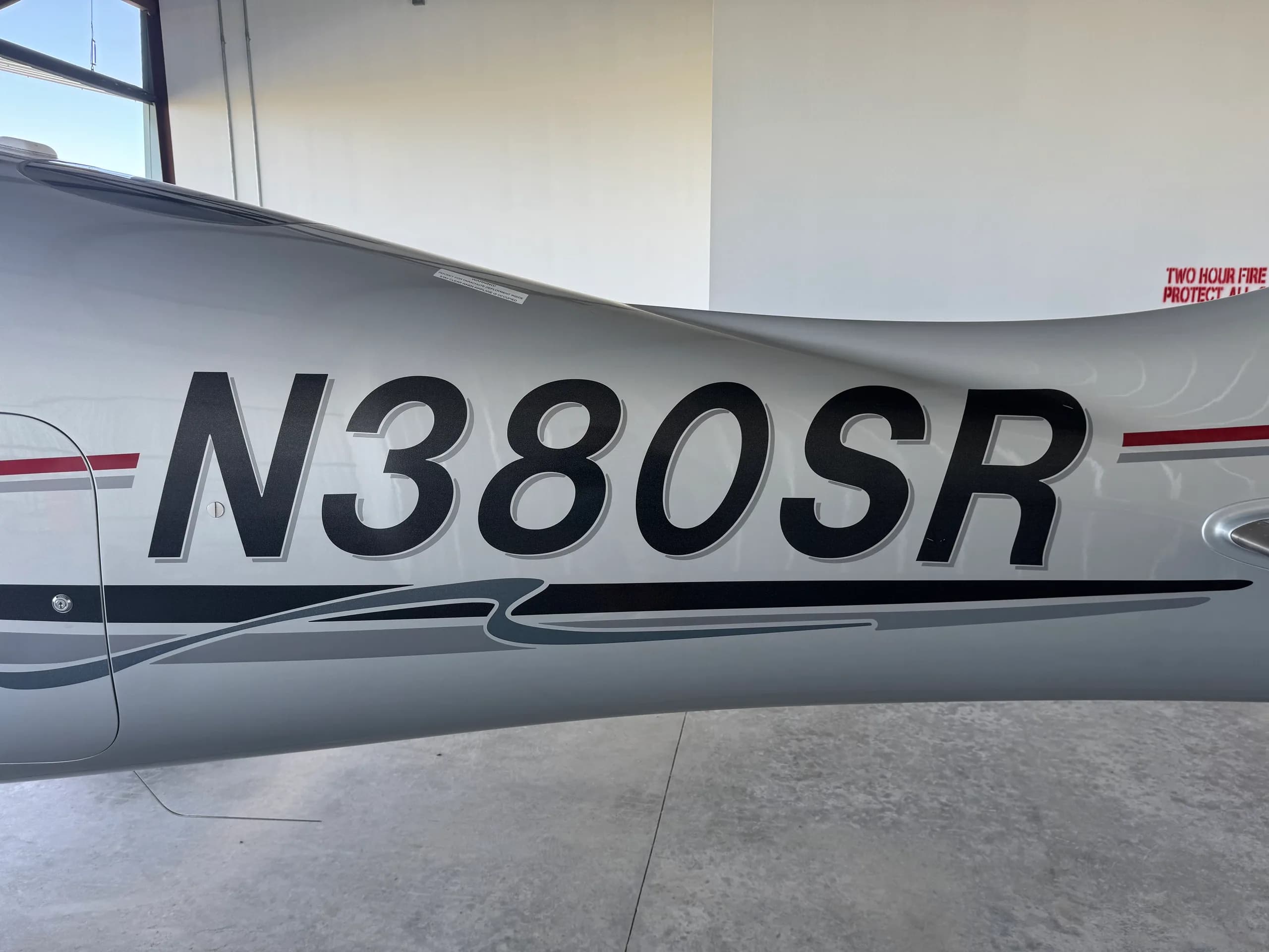 A close-up view of the N380SR registration on the silver fuselage of a Cirrus SR22 Generation Three aircraft.