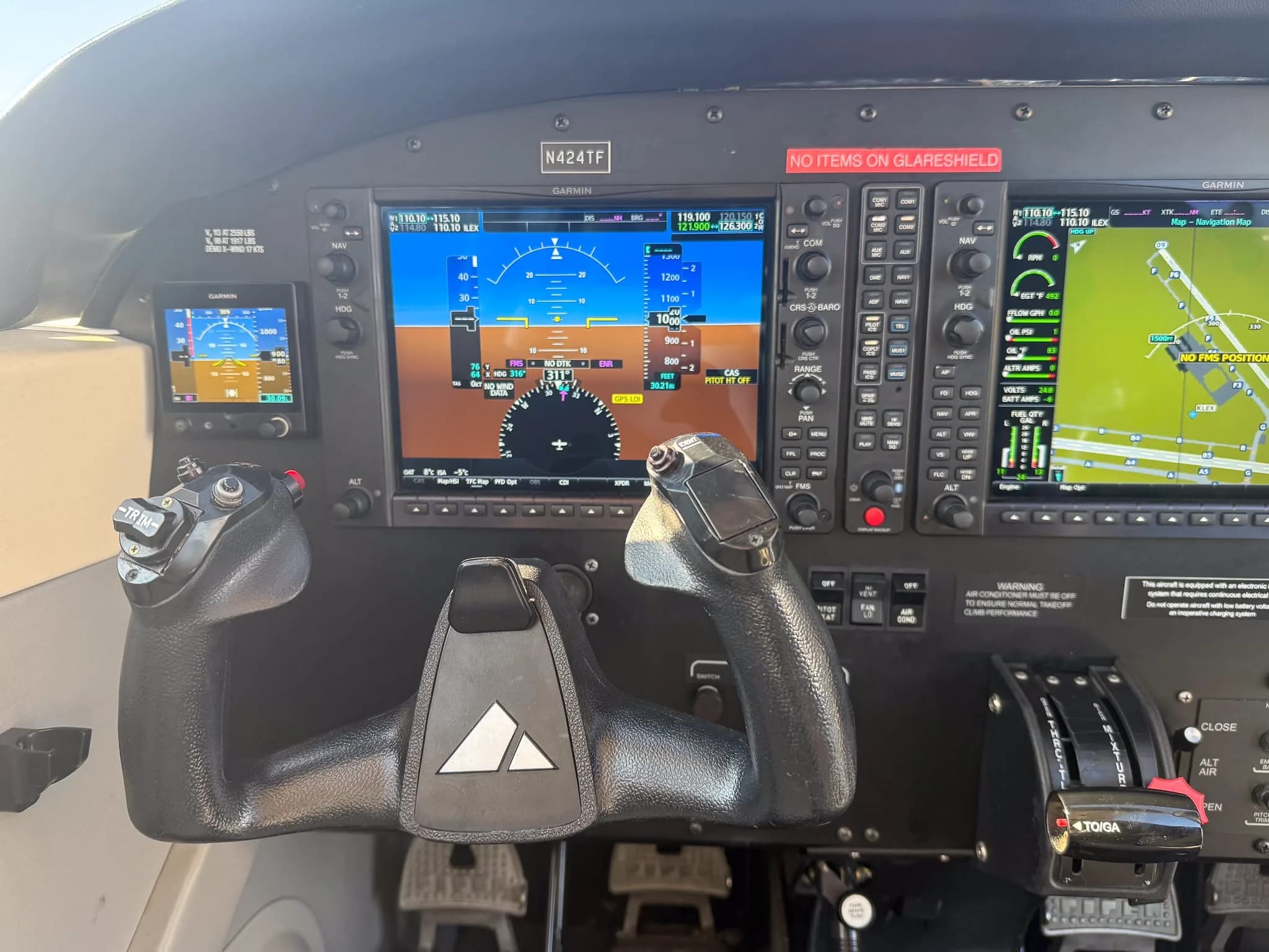A close-up view of the Piper Archer TX cockpit with Garmin G1000 NXi displays and control yokes, showing N424TF on the panel.