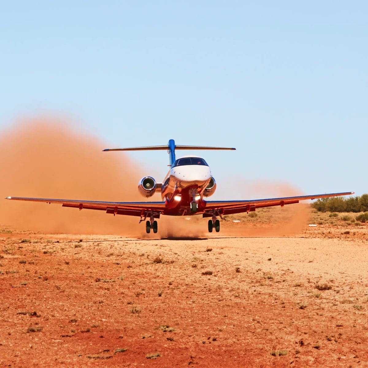 A Pilatus PC-24 aircraft taking off from a dusty runway.