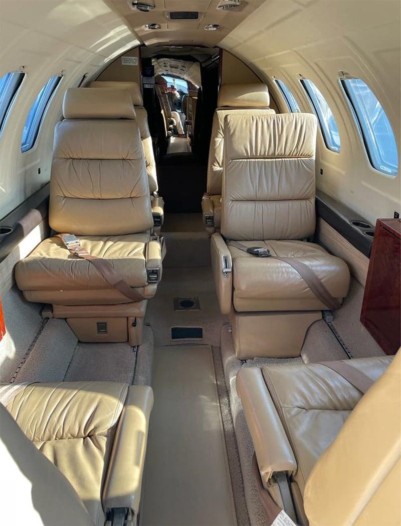 The interior of a Cessna Citation CJ3 features tan leather seats and a center aisle.