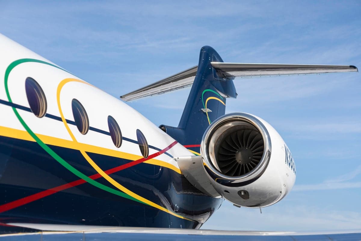 Close up of the tail and engine of a Gulfstream jet with colorful stripes.