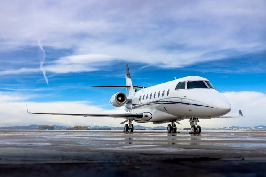A Gulfstream aircraft is parked on the tarmac with a cloudy sky overhead.