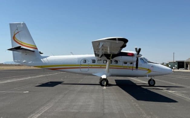 Side view of a Twin Otter aircraft with white and yellow paint scheme.