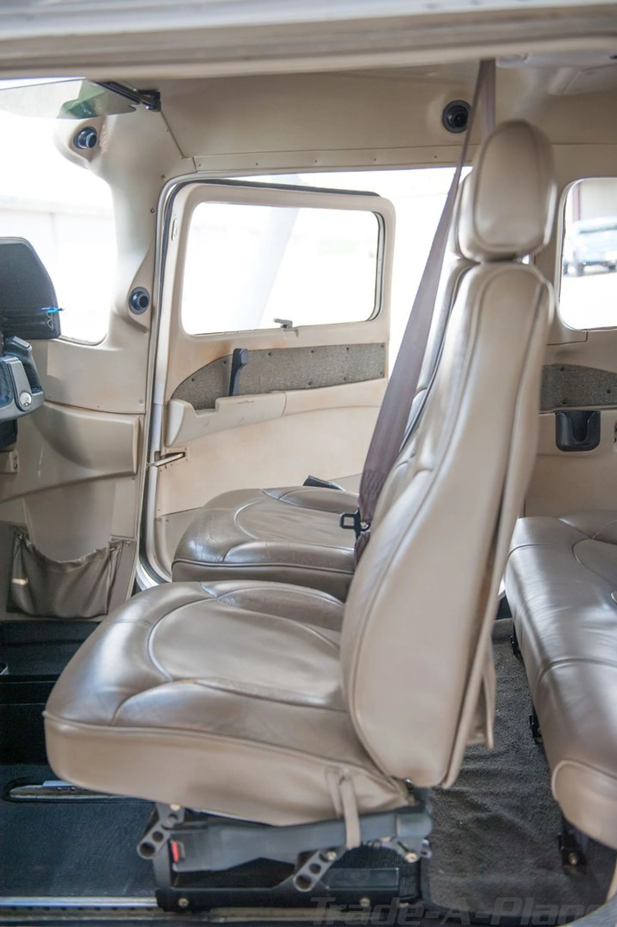The tan leather interior of a Cessna Skylane, showing the front passenger seat and an open door.