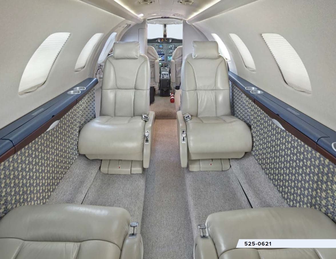 The interior of the aircraft features leather seats and a view of the cockpit.