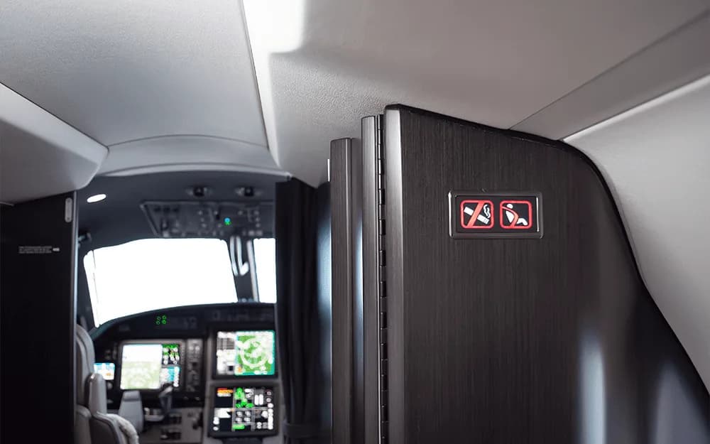 A close-up of the cabin divider with seatbelt signs, looking towards the cockpit of the Pilatus PC-12 NGX.