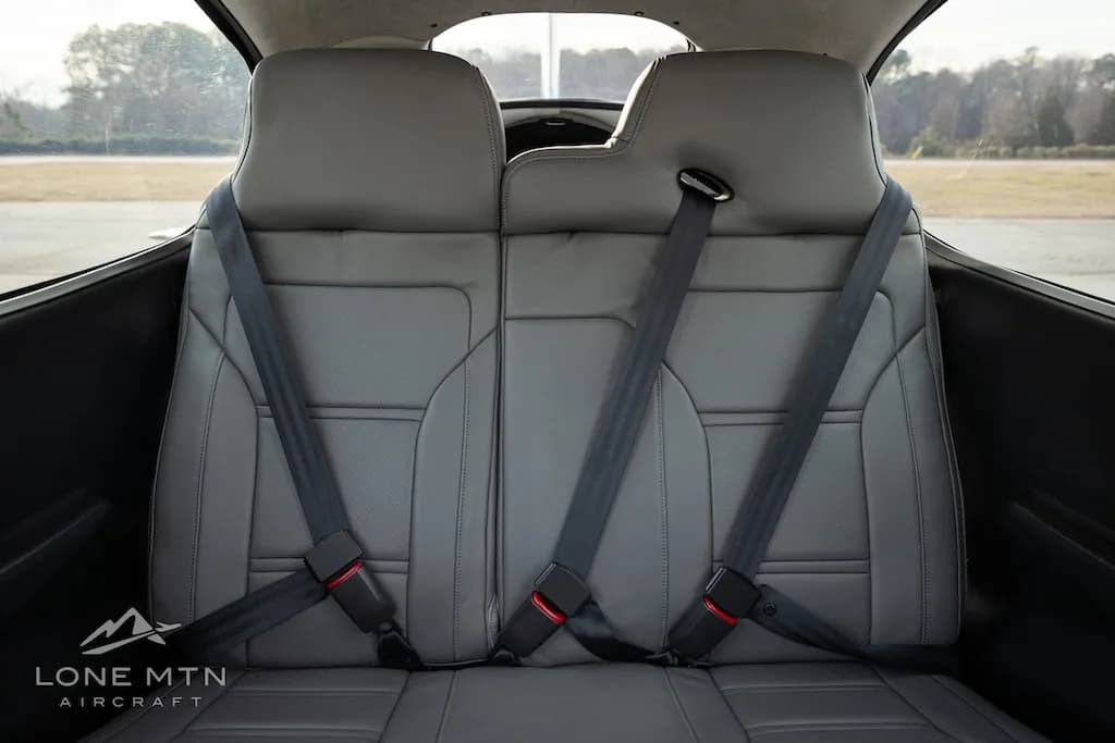 The gray leather rear seats of the Cirrus SR22 aircraft cabin with seatbelts fastened.