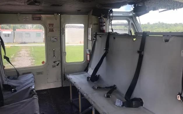 The interior cabin of a helicopter showing utility seating and a fire extinguisher mounted near the door.