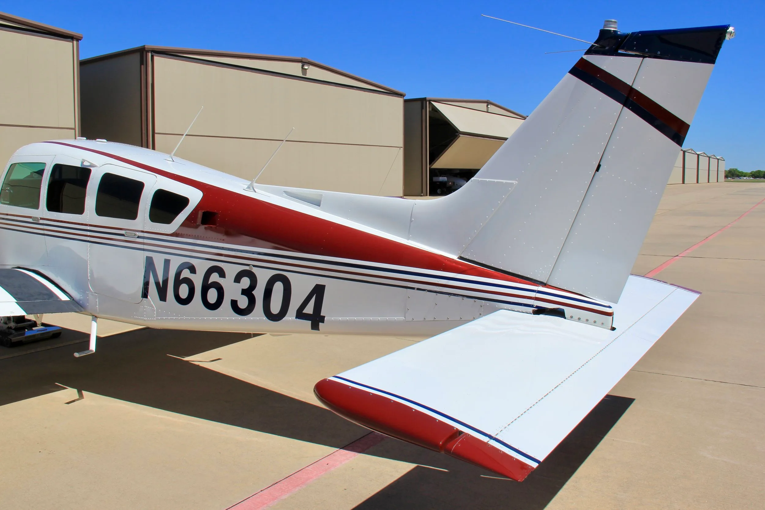 A close-up view of the tail section and registration number N66304 on the white, blue, and red aircraft.