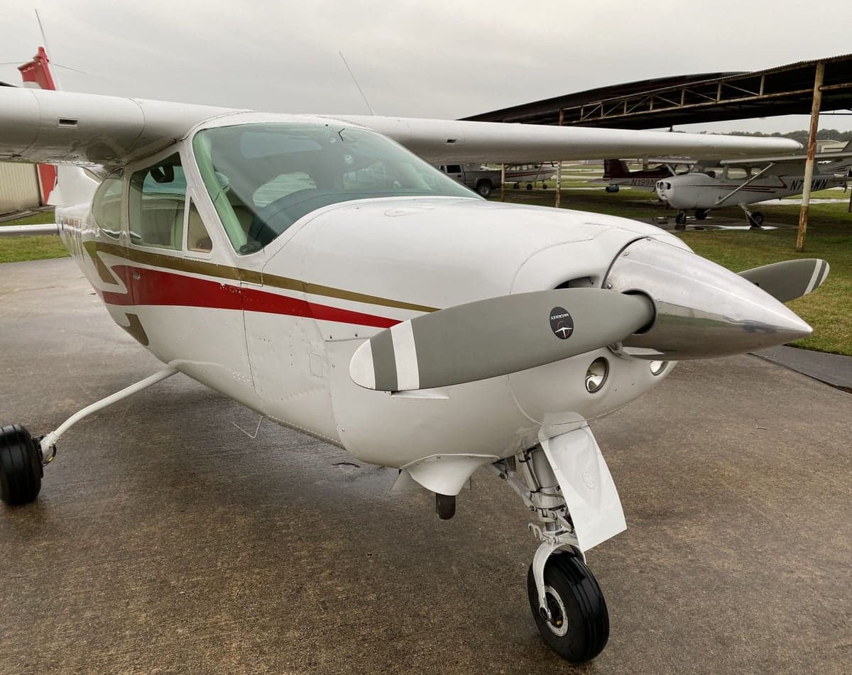 A Cessna 177RG Cardinal with a white and red paint scheme is parked on the tarmac.