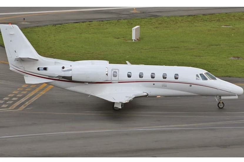 A white Cessna Citation XLS aircraft is on the tarmac with a red stripe.