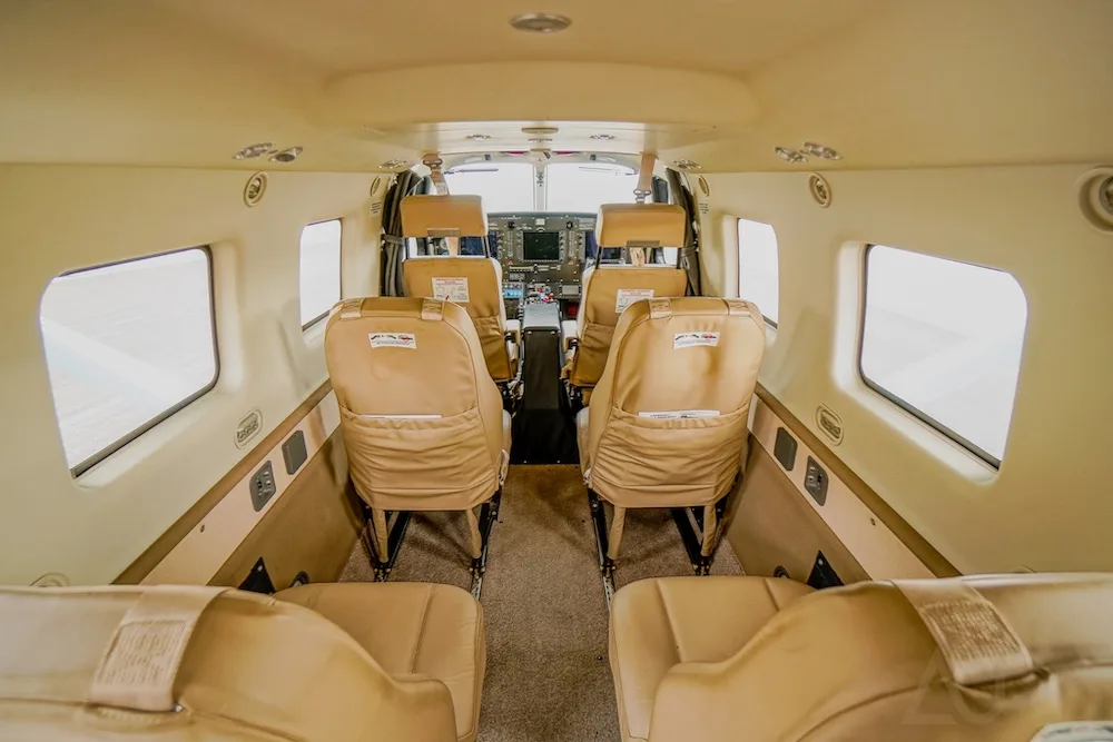 The interior cabin of an aircraft with tan leather seats, looking forward towards the cockpit.