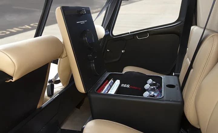 The interior of a Robinson R66 Turbine helicopter with tan seats and a center console.
