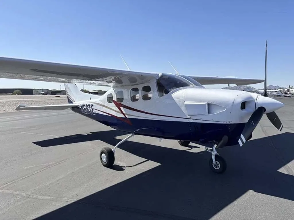 A front-quarter view of the white and blue Cessna 210 Centurion with registration N66TE on an airfield.