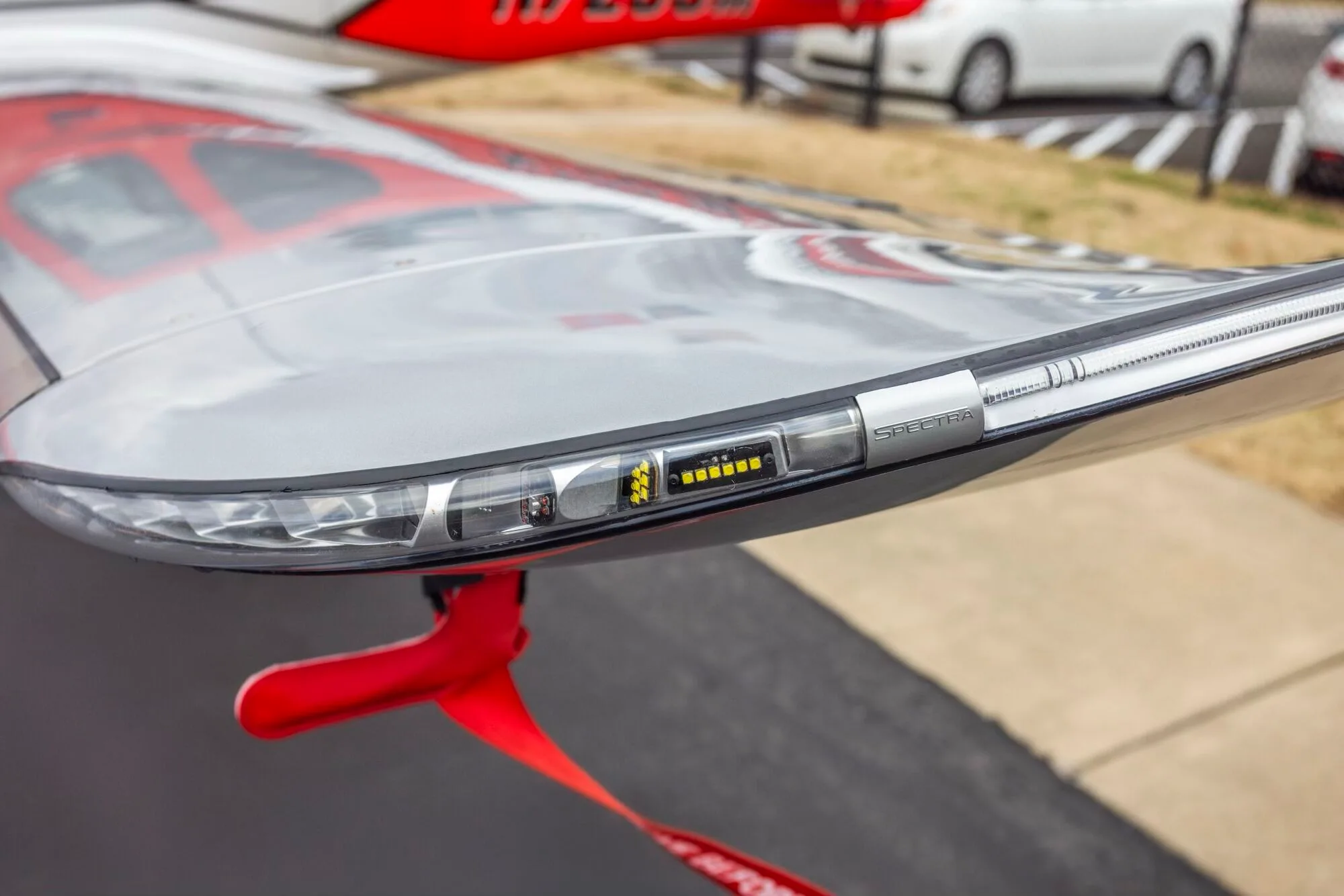 A detailed close-up of the "Spectra" wingtip light on a red and silver Cirrus SR22 aircraft.