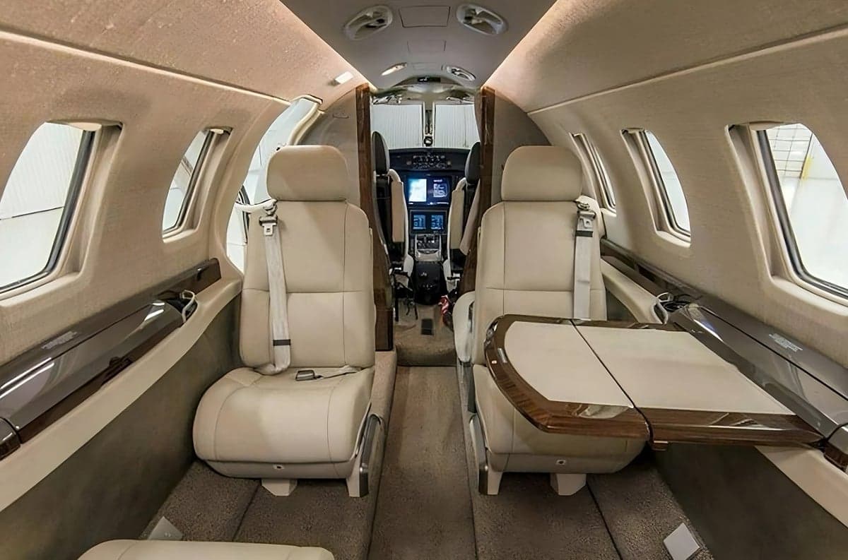 Forward-facing seats and a table in the cabin of a jet.