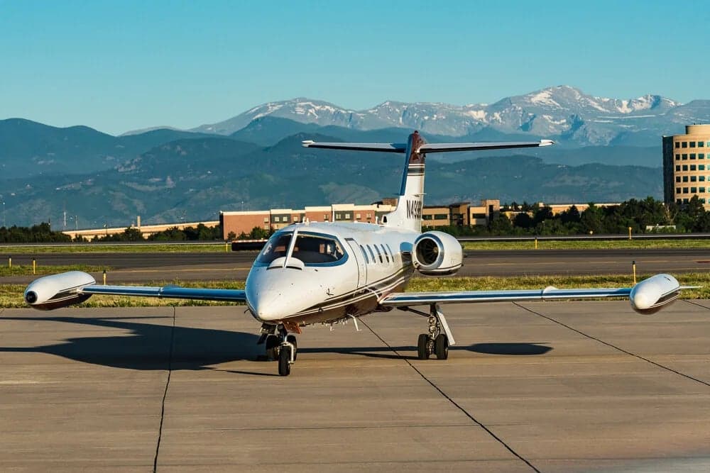 A Learjet 31A with registration N499BS is parked on the tarmac with mountains in the background.