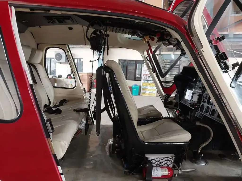 The interior of the helicopter showing the light beige seats and a partial view of the cockpit controls.