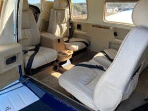 Aircraft interior featuring cream-colored leather seats and a center console.