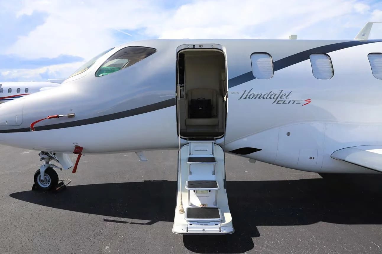 A close-up of the front fuselage of a HondaJet Elite S (N420XE) with the main cabin door open and stairs extended.