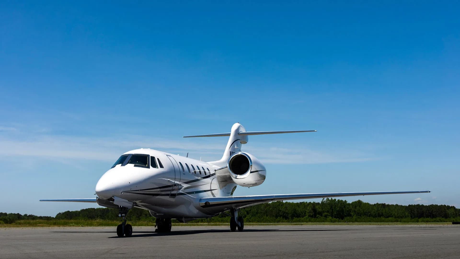 A white jet aircraft parked on the tarmac under a blue sky.