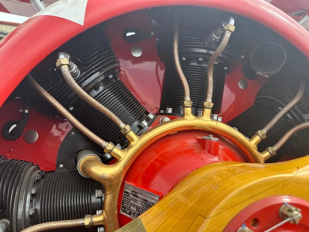 A close-up view of the radial engine cylinders and brass manifold on the red biplane.
