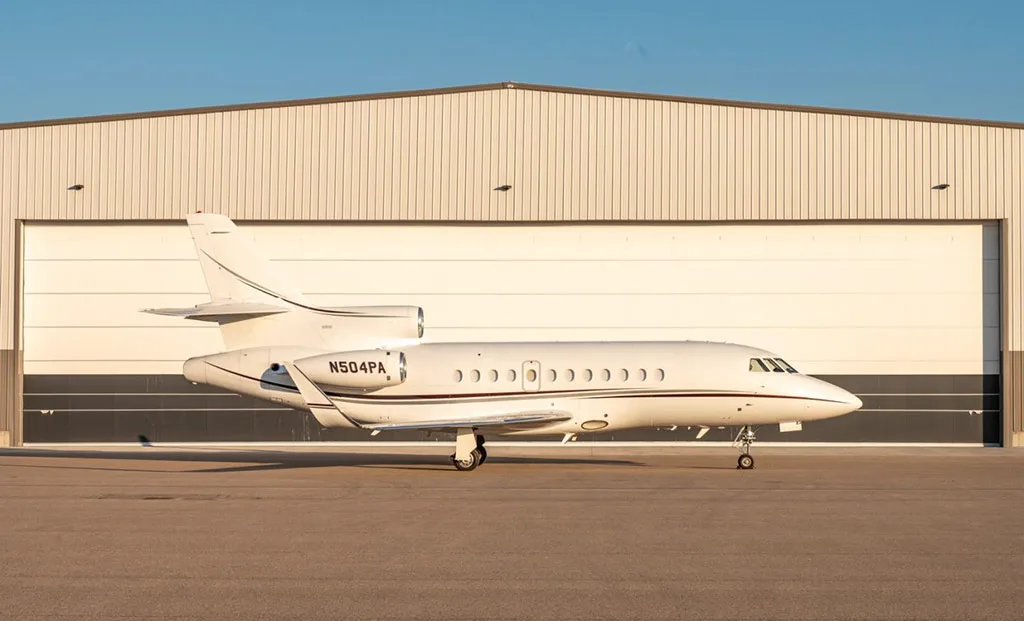 A Dassault Falcon 900EX business jet, registration N504PA, parked on the tarmac in front of a hangar.