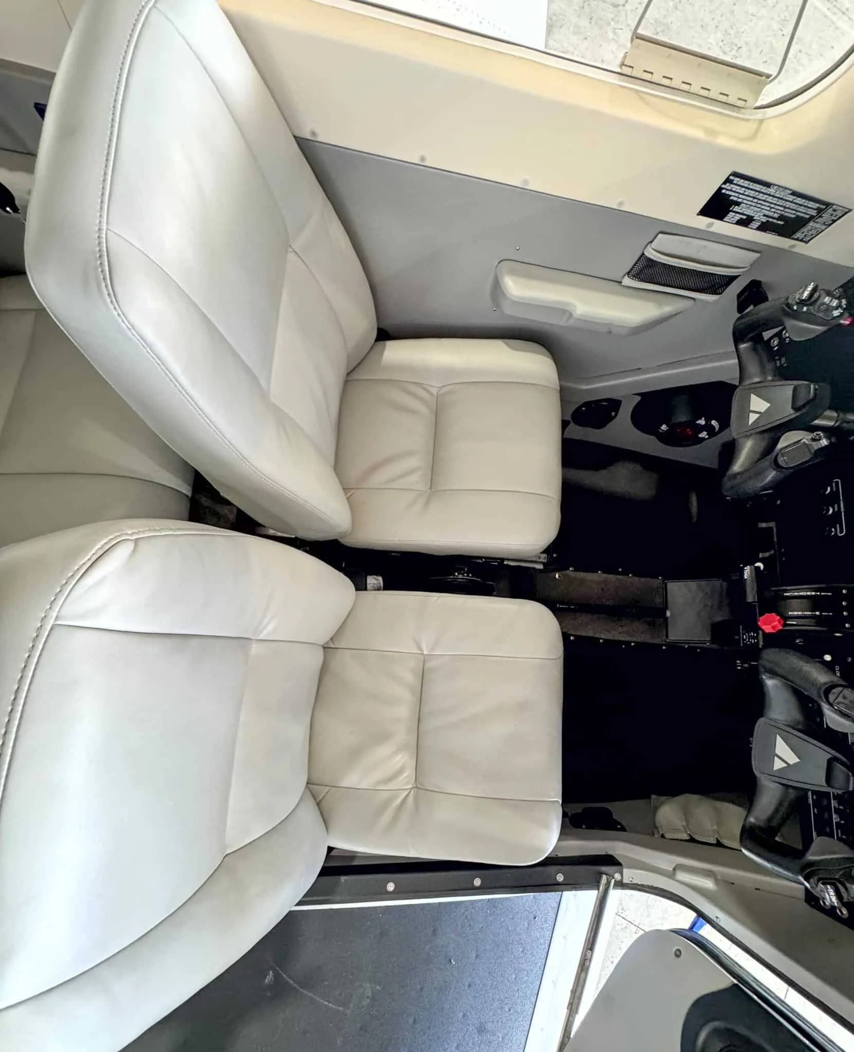 An overhead view of the light gray leather front seats in the aircraft cabin.
