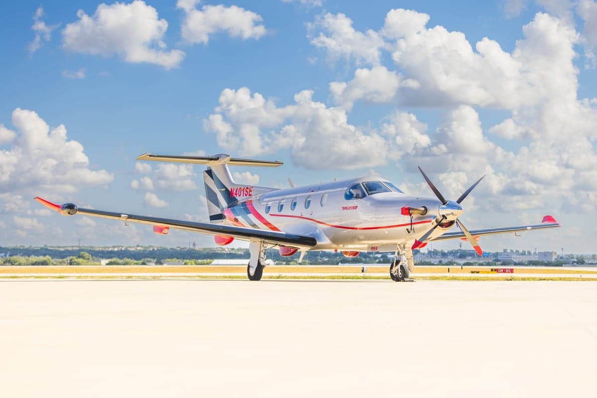 A Pilatus PC-12NG aircraft on the tarmac with a silver and red paint scheme.