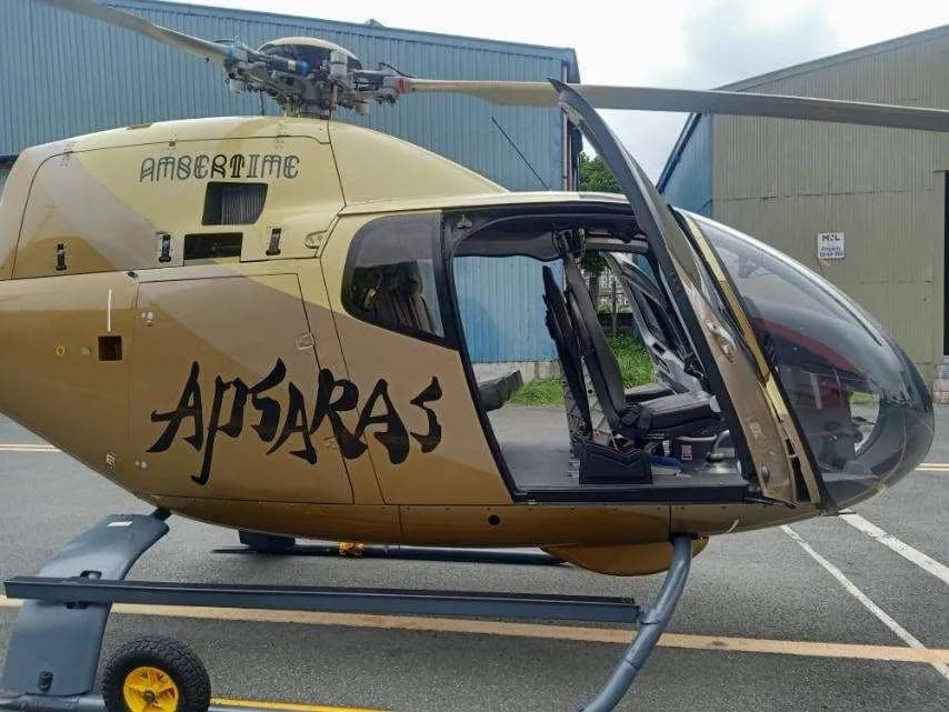 Side view of a gold helicopter with the door open, showing the interior.