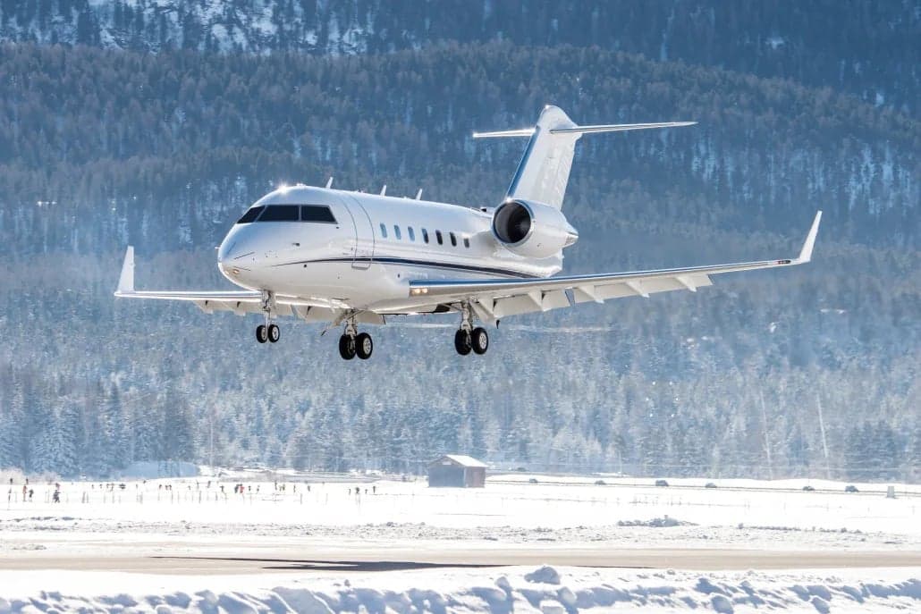 A Bombardier Challenger jet lands on a snowy runway.