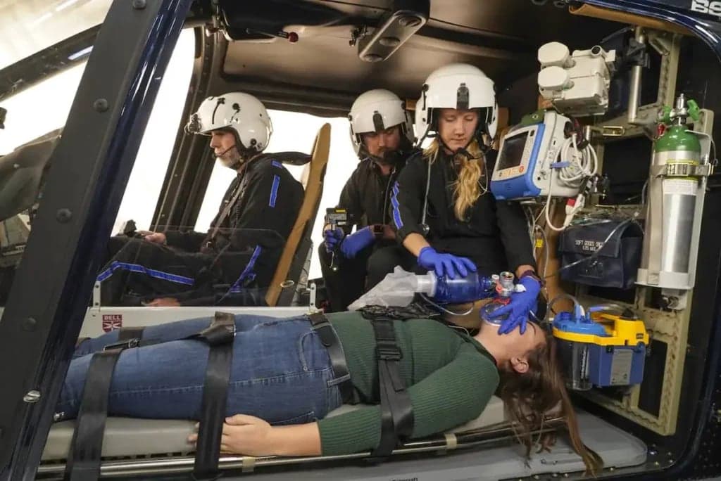 Interior view of a helicopter with medical personnel attending to a patient on a stretcher.