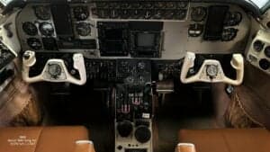 The cockpit of a Beech B90 King Air aircraft is shown with instrument panel details and seats.