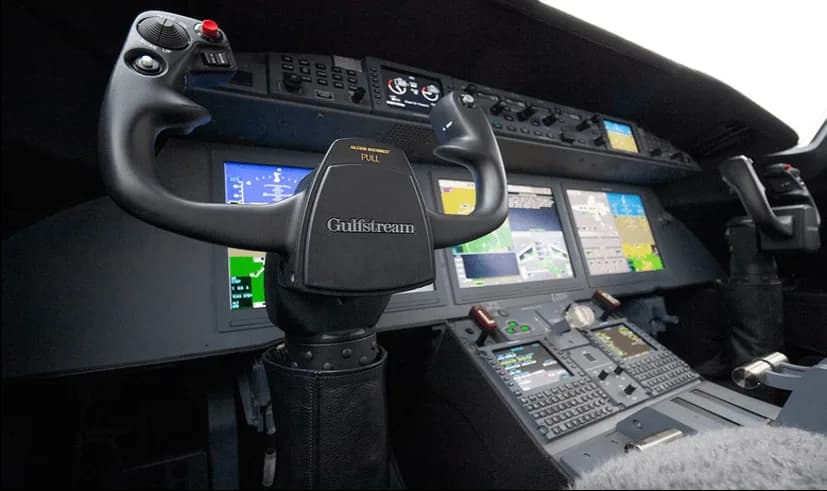 The cockpit of a Gulfstream aircraft, showing the instrument panel with multiple displays and the pilot's yoke.