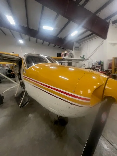 Close up of the front of a yellow and white Cessna Skymaster in a hangar.