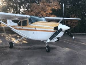 A close-up of a Cessna 182RG with a white and gold paint scheme.
