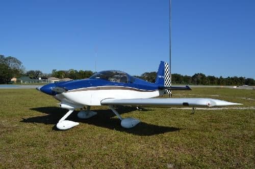 A blue and white aircraft is parked on a grassy field.