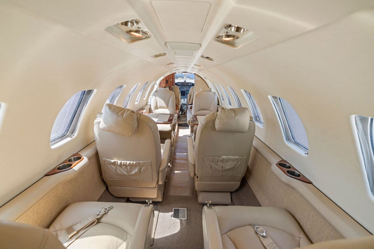 The aircraft's interior features light-colored leather seats and carpet.