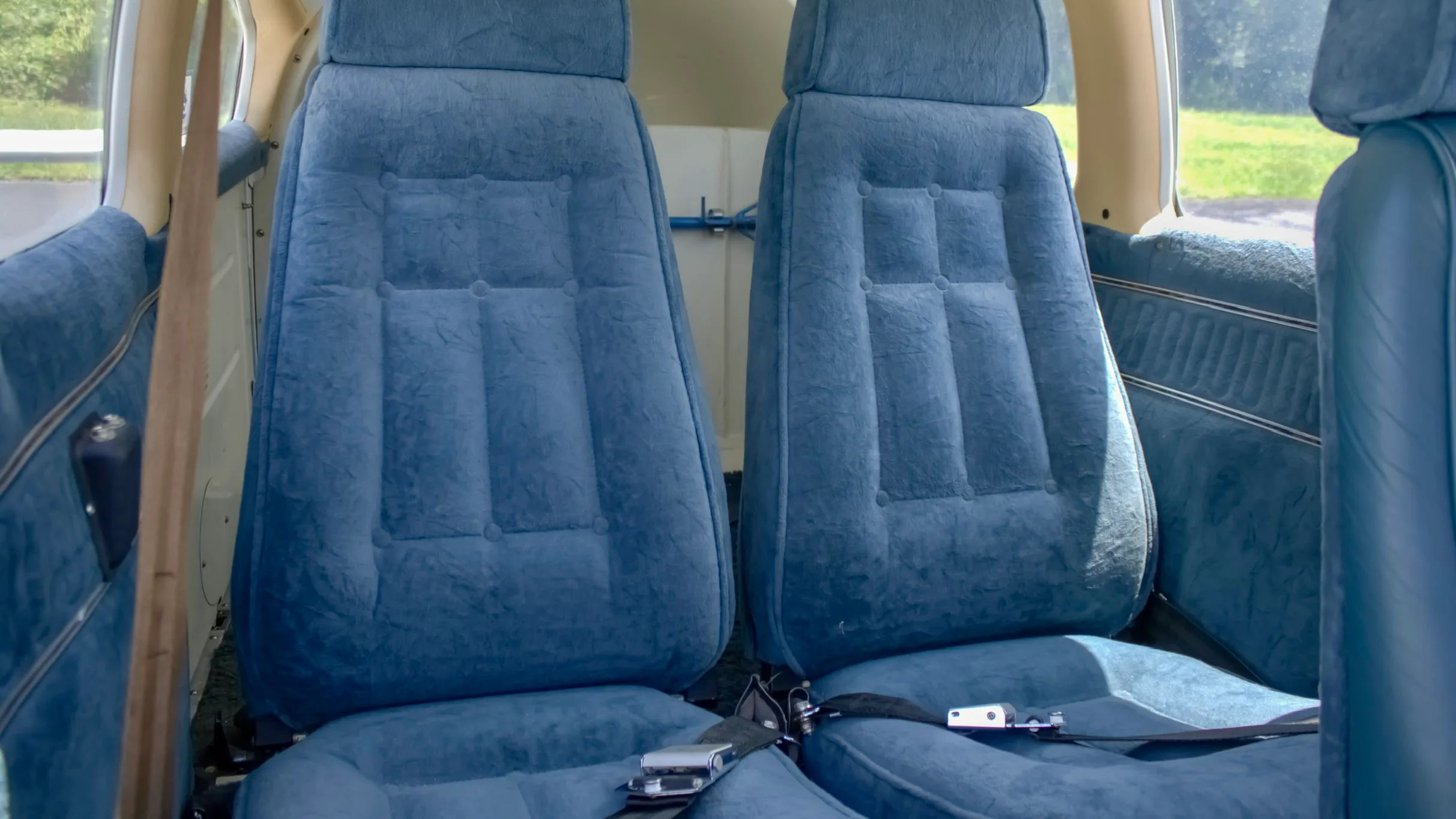 Two blue upholstered passenger seats in the cabin of a small aircraft.