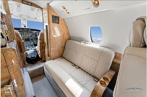 A view of the aircraft's interior, featuring leather seats and a view into the cockpit.