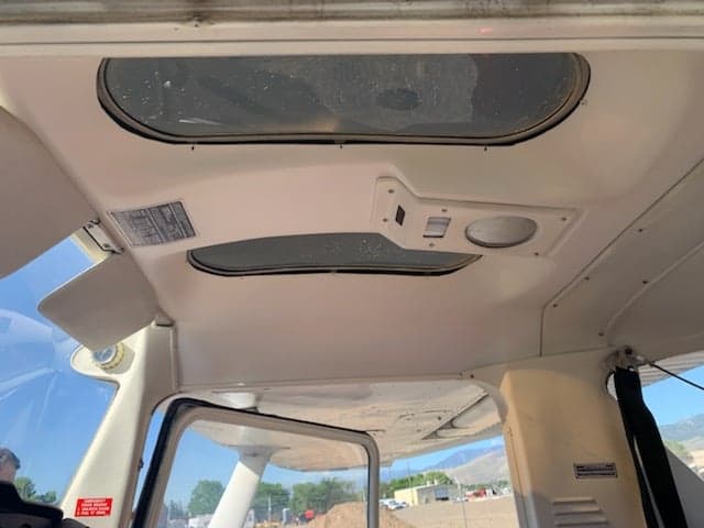 The interior ceiling of a small aircraft, showing overhead windows and light fixtures.