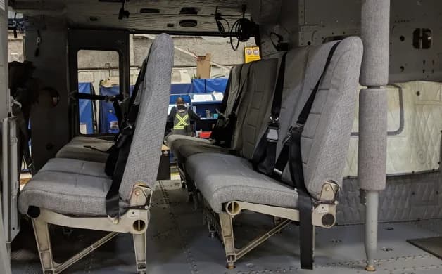 Two rows of grey fabric passenger seats inside a helicopter cabin.