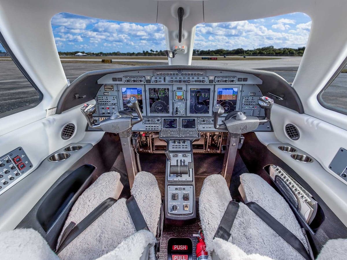 View of the Citation CJ4 cockpit featuring the instrument panel and sheepskin seat covers.