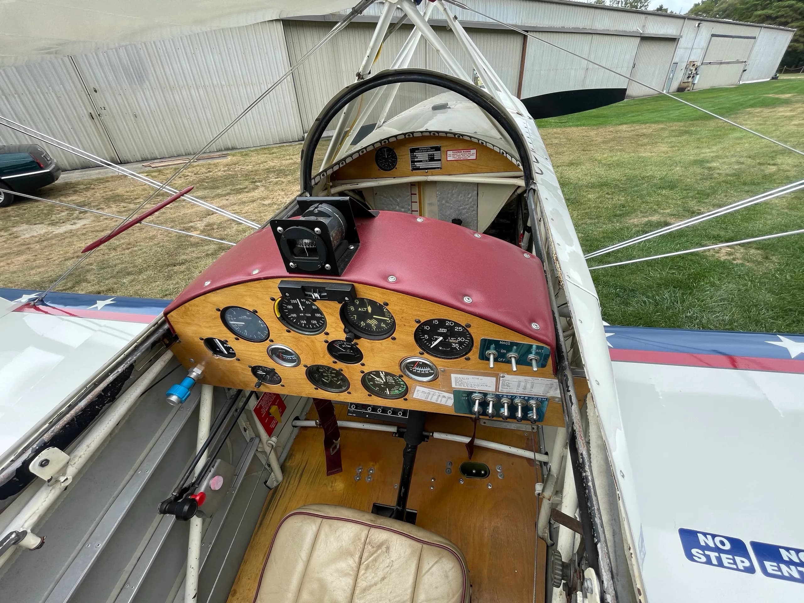 An overhead view of the Acro Sport II Skybolt's cockpit, showing the wooden instrument panel with gauges and a tan seat.