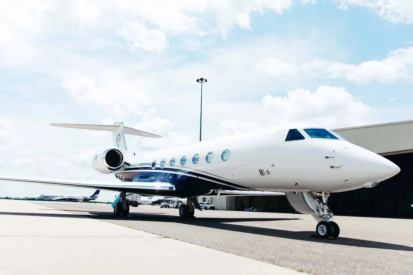 A front-side view of the white and blue Gulfstream G550 business jet, registration N279WR, parked on the tarmac.